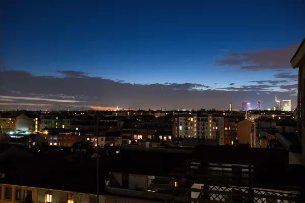 Milan's rooftops and lights at dusk, seen from the terrace