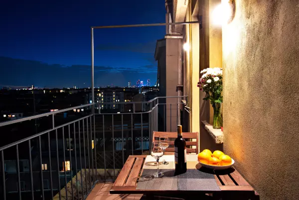 Table and flowers on the terrace at night, with the lights of Milan beyond