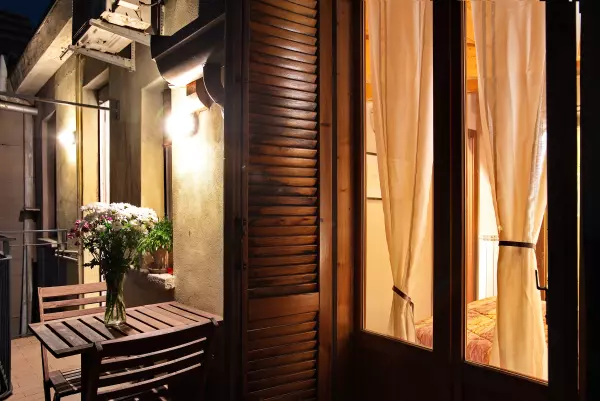 The bedroom's French door opening onto the terrace at night