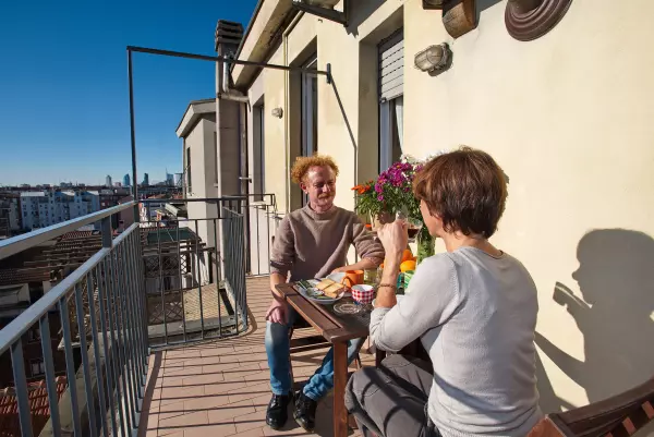 Couple having breakfast in the sun on the terrace of Milan Skyline Apartment, Milan Città Studi