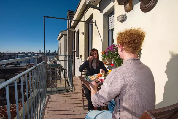 Couple having breakfast in the sun on the terrace of Milan Skyline Apartment, Milan Città Studi